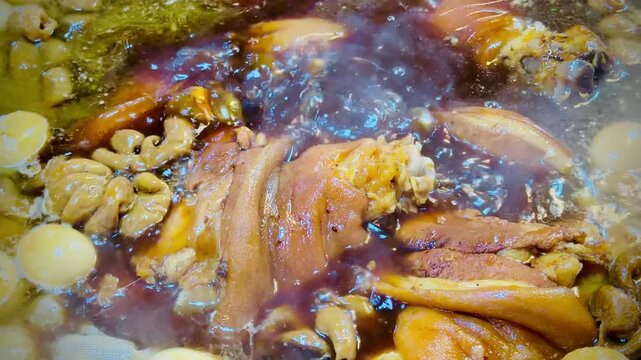Traditional Thai-style braised pork leg simmering in a rich dark soy and herbal broth with boiled eggs. Authentic Asian street food captured in close-up detail.
