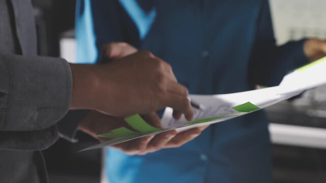 Group of young Asian uxui designers working together pointing at computer screen analyzing mobile app interface wireframes while working in a modern office