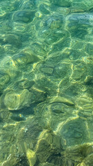 Rippling emerald waters dance over hidden stones, evoking tranquility of World Water Day and Gaia's gentle embrace