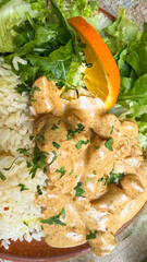 Creamy turmeric chicken dances with fragrant rice beside verdant greens and citrus, perfect for Holi festivities or culinary escapades