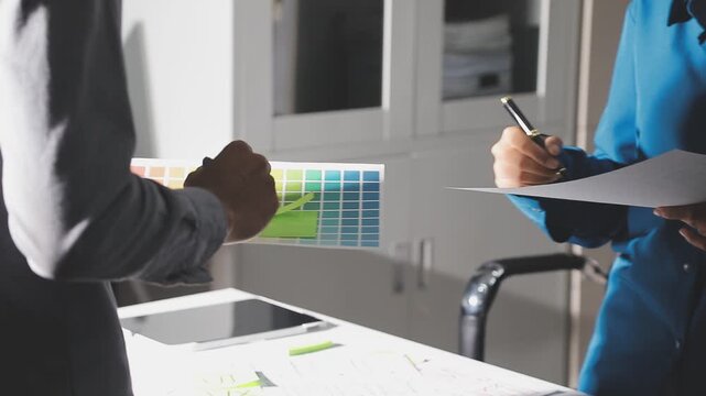Group of young Asian uxui designers working together pointing at computer screen analyzing mobile app interface wireframes while working in a modern office