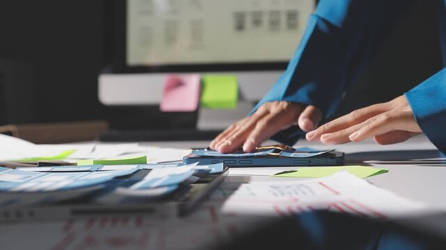 Group of young Asian uxui designers working together pointing at computer screen analyzing mobile app interface wireframes while working in a modern office