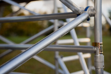 Close-up of metallic scaffolding frame structure outdoors, illustrating precision engineering, modular connection joints, and durable aluminum framework used in construction, maintenance