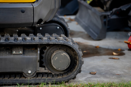 Compact excavator track detail on concrete surface, showing industrial strength, modern machinery design, and durable construction equipment used for groundwork and infrastructure development