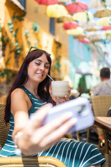 Woman making selfie with phone in outdoor cafe, enjoying cocktail and travel lifestyle during summer vacation