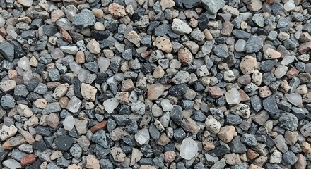 Close-up overhead view of a textured, multi-colored aggregate of crushed stone and gravel, showcasing diverse mineral compositions and rough surfaces.