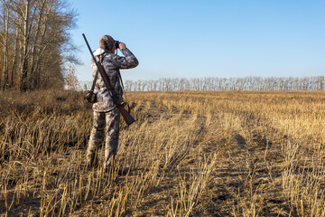 Man hunter looking through binoculars,  searching for his next target. Autumn hunting season.