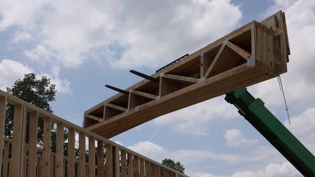 Worker positions wooden beams telehandler using machinery on construction site location