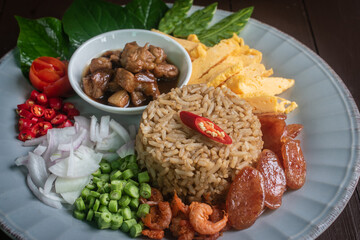 Beautifully arranged Thai shrimp paste fried rice, known as Khao Kluk Kapi, served with traditional side ingredients such as sweet pork, sliced omelet, red chili, shallots, dried shrimp, green beans, 