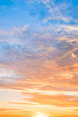 Fototapeta premium Sunset or sunrise sky with a vibrant gradient of orange, gold, and soft blue. Clear atmosphere with wispy clouds. Peaceful, natural light background. hope, freedom, new day Concepts, Vertical