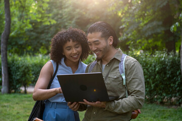 Interracial couple studying, working remotely in park