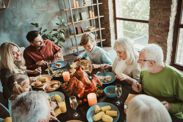 A warm family thanksgiving dinner around a big turkey with generations gathering together for a...