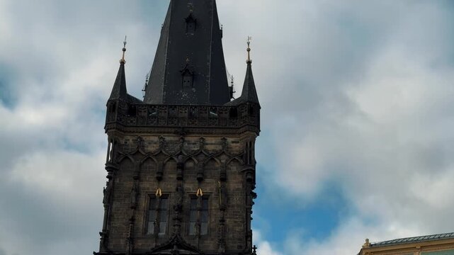 The Gothic Powder Tower stands beside the Art Nouveau Municipal House in Prague's city center. Architectural contrast highlights this historical intersection.