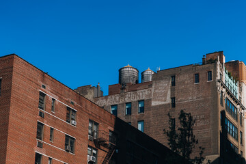 A row of brick buildings with a blue sky in the background. The buildings are old and have a rustic feel to them