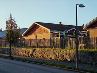 Obraz premium Road along beautiful and cozy residential houses in Sweden during golden hour with a warm autumn atmosphere