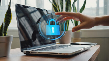 Cybersecurity Concern: A hand reaches toward a laptop screen, overlaid with a digital padlock, symbolizing the need for digital security. The image captures the modern-day struggle to protect data. 