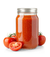 Clear glass jar filled with tomato Sauce with metallic cap and surrounded by fresh tomatoes