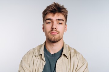 Young man with styled hair poses for a portrait against a light background in a casual outfit during daylight hours