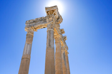 Majestic Ancient Pillars Bathed in Bright Sunlight Against a Clear Blue Sky, Highlighting Historical Architectural Grandeur