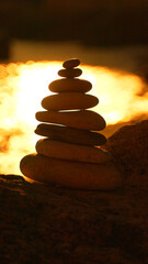 Obraz premium Stones balance sunset, serene rock cairn stacked against golden ocean light at dusk with peaceful copy space.