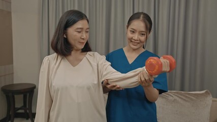 asian female caregiver assisting senior woman with physical therapy exercise at home during rehabilitation process to improve mobility strength and overall health care support in daily life
