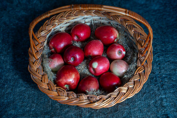 A close-up shot of fresh, ripe red apples in a rustic wicker basket, resting on a bed of dry straw....