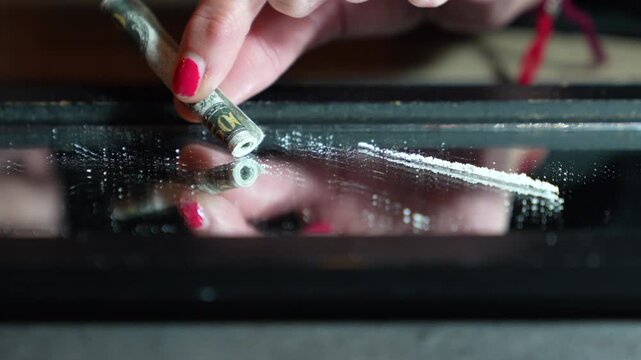 Lines of cocaine being snorted through tube on mirror