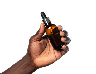 Dark-skinned hand holding a brown glass bottle with a dropper against black