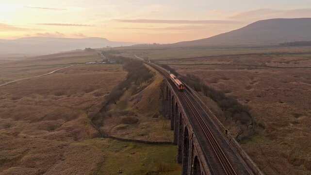 Aerial view of Ribblehead viaduct in the early sunrise morning. Drone POV of Yorkshire Dales National Park located in the United Kingdom. 
