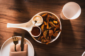 Baked potato with spices, herbs and ketchup in a plate on the wooden table. 