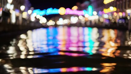 Nighttime view of a canal with colorful reflections from illuminated buildings. - Powered by Adobe