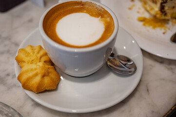Freshly brewed cappuccino in a white cup on a saucer