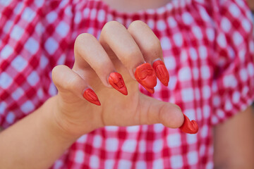 plasticine nails on fingers, little girl with red nails on her fingers made of plasticine