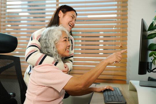 granddaughter teaches her grandmother work with computer at home