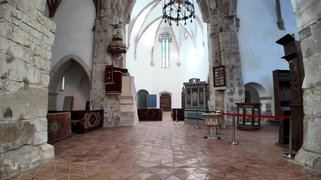 Prejmer Fortified Church interior in Transylvania, Romania, displaying its historic altar, ornate baptismal font, and religious furnishings. UNESCO site of Romania