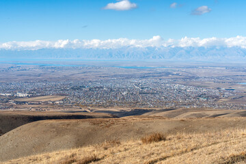 A high-angle panoramic autumn view of Karakol city photographed from rolling hills to the south.