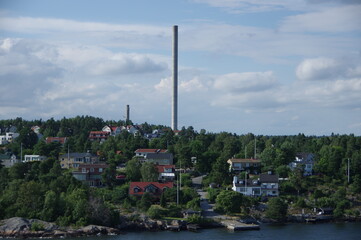 Obraz premium tall industrial chimneys high flue stack with residential area at stockholm archipelago in sweden