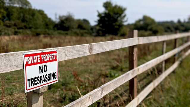 Private Property No Trespassing warning sign clearly posted on a long wooden fence, symbolizing boundaries, security, and rural land ownership