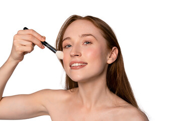 Fototapeta premium Woman applying makeup with a brush in a bright setting enhancing her natural beauty and glowing skin