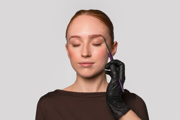Beauty expert shaping eyebrows on a client in a modern salon setting during daylight hours