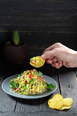 Eat a salad with chips. Mexican salad and chips. Hand and salad.