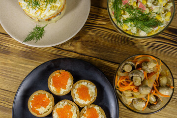 Tartlets with red caviar and festive salads on a wooden table. Festive food