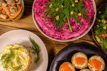 Tartlets with red caviar and festive salads on a wooden table. Festive food