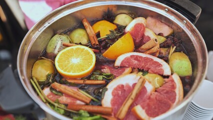 Chef preparing mulled wine with various fruits and spices in a pot