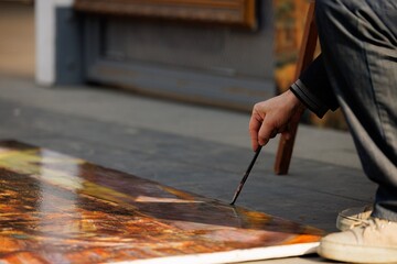 Obraz premium A talented individual is passionately painting on the ground, surrounded by the warm glow of autumn sunlight.