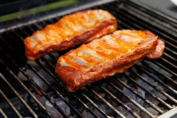 Tender ribs coated with marinade cooking on a grill at a lively outdoor barbecue with friends and family.