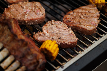 Grilling juicy steaks alongside fresh corn on a warm sunny afternoon, friends enjoying the lively outdoor atmosphere