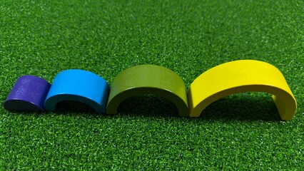 Three colorful wooden arch blocks arranged on a green surface