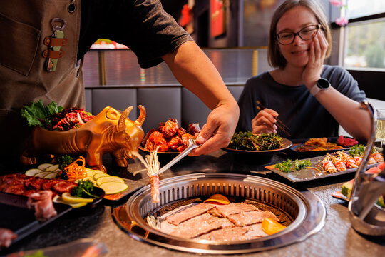Friends gather by a grill with fresh ingredients, sharing laughter and delicious dishes in a lively atmosphere.