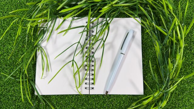 White Notebook and Pen on Green with Fresh Greenery